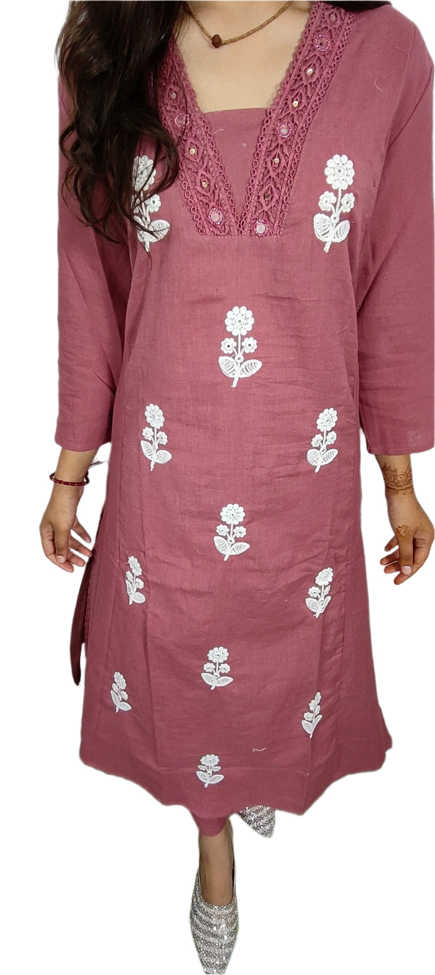 Pink embroidered dress with white floral patterns worn by a person on a grassy surface.